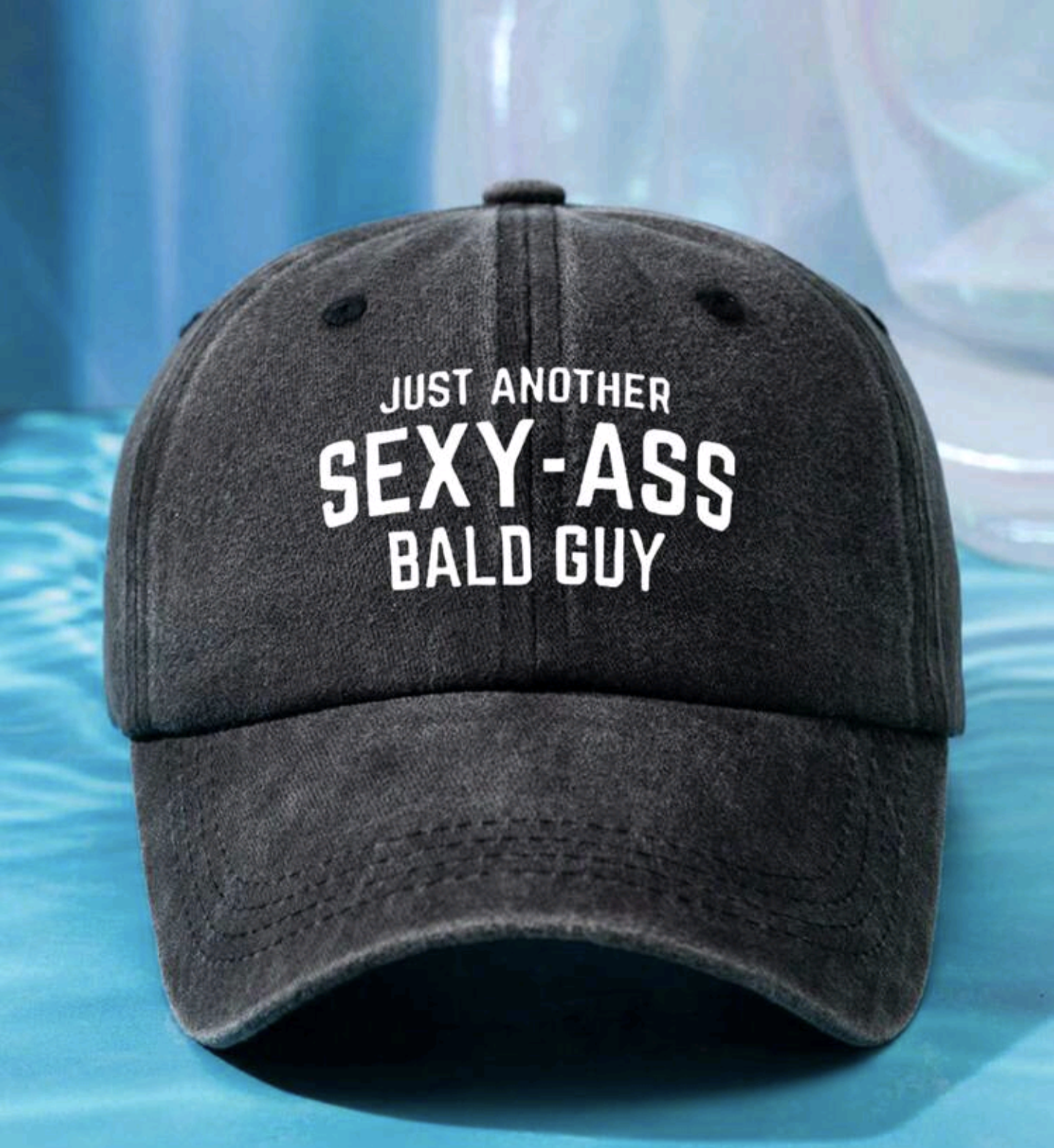 A gray baseball cap with the text 'JUST ANOTHER SEXY-ASS BALD GUY' printed on the front.